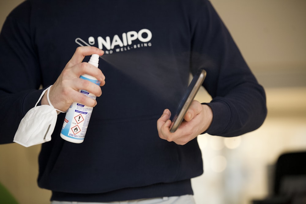 person in black sweater holding blue and white bottle