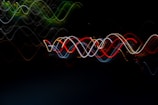 A series of vibrant, wavy light trails create a mesmerizing pattern against a dark background. The intertwining lines reveal a motion effect with colors such as red, blue, green, and yellow, forming an abstract visual spectacle.