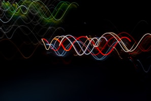 A series of vibrant, wavy light trails create a mesmerizing pattern against a dark background. The intertwining lines reveal a motion effect with colors such as red, blue, green, and yellow, forming an abstract visual spectacle.
