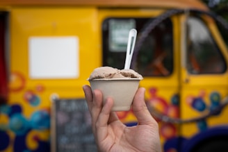 A delivery person handing over a premium ice cream cup in a clear disposable container at a customer's doorstep.