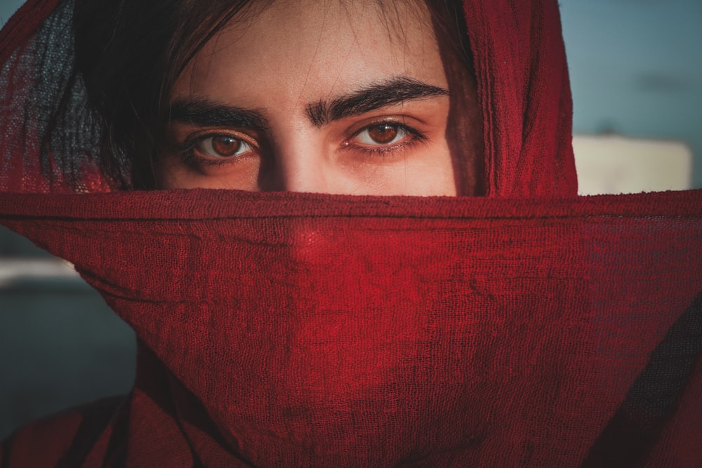 woman covering her face with red textile