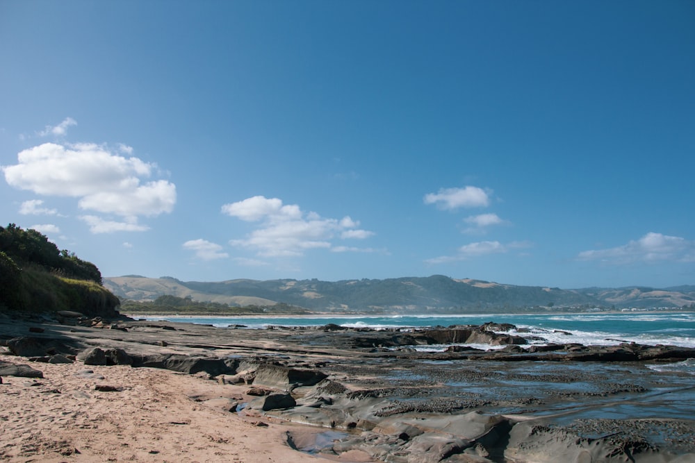 brown rocks on seashore under blue sky during daytime