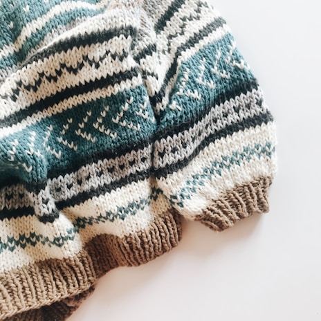 A cozy knitted sweater with a pattern of horizontal stripes in various colors. The texture is thick and the design includes alternating colors with geometric motifs.