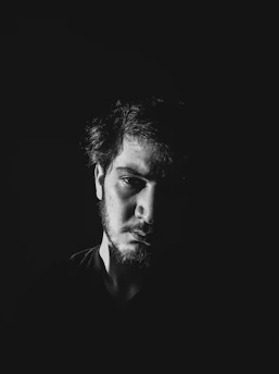 Dramatic portrait of Diego R. Fernandez illuminated by moody stage lighting, capturing his intense artistic presence.