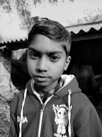 Black and white photo of a young adult wearing a hoodie with the slogan 'last christmas before deadlines' against a minimalist urban backdrop.