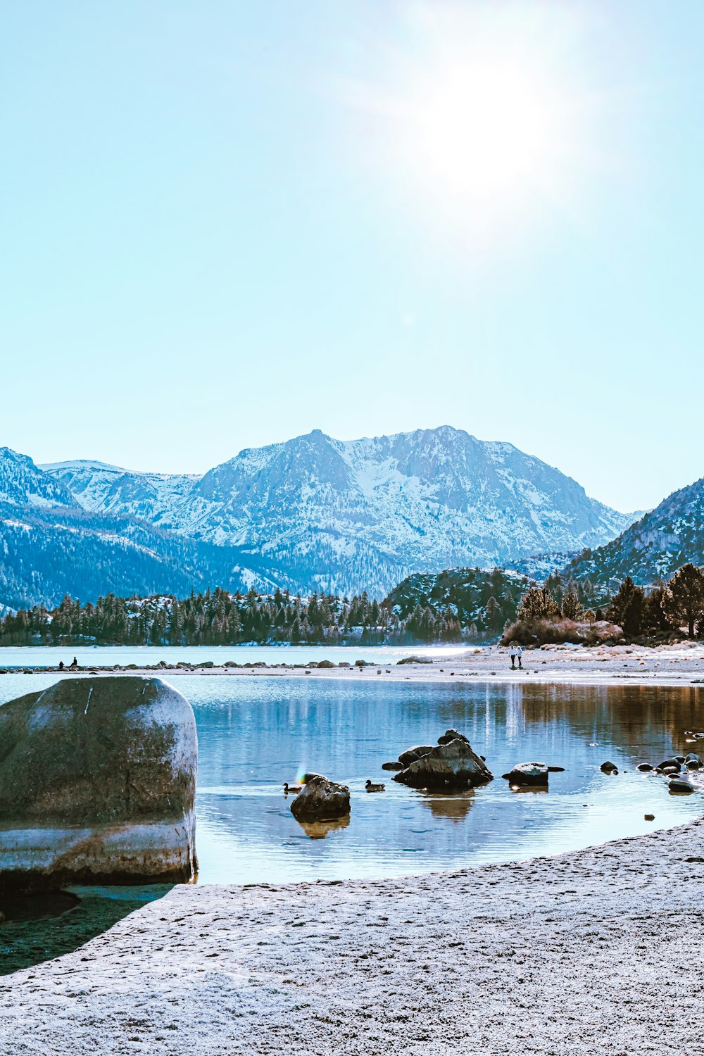 lake near mountain under white sky during daytime