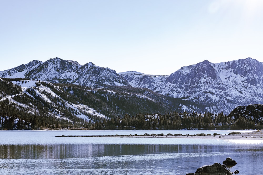 snow covered mountain near body of water during daytime