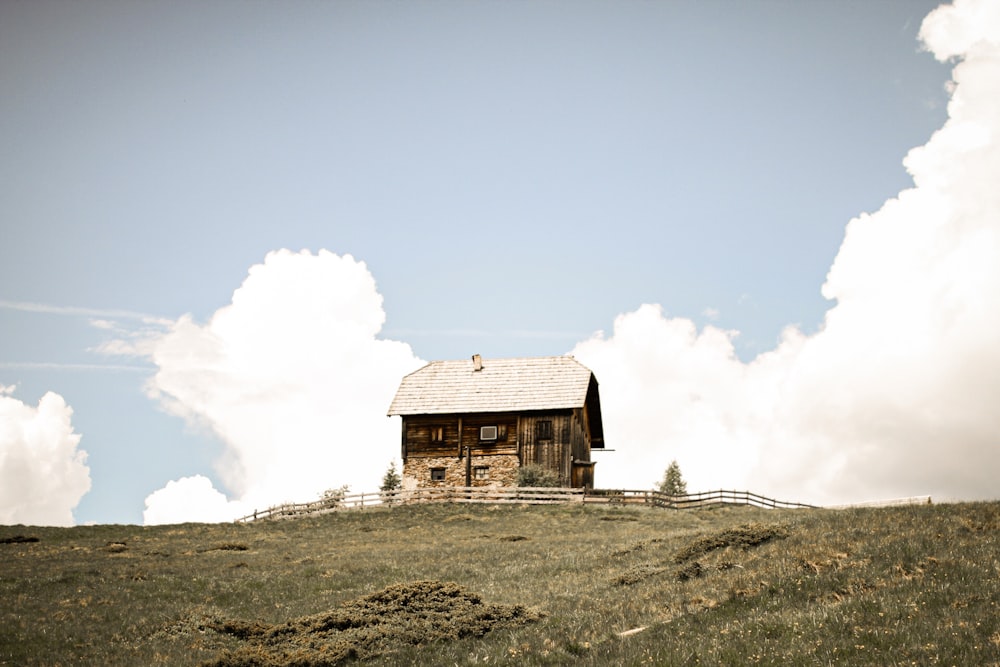 昼間は白い雲の下の丘の上の茶色い木造家屋