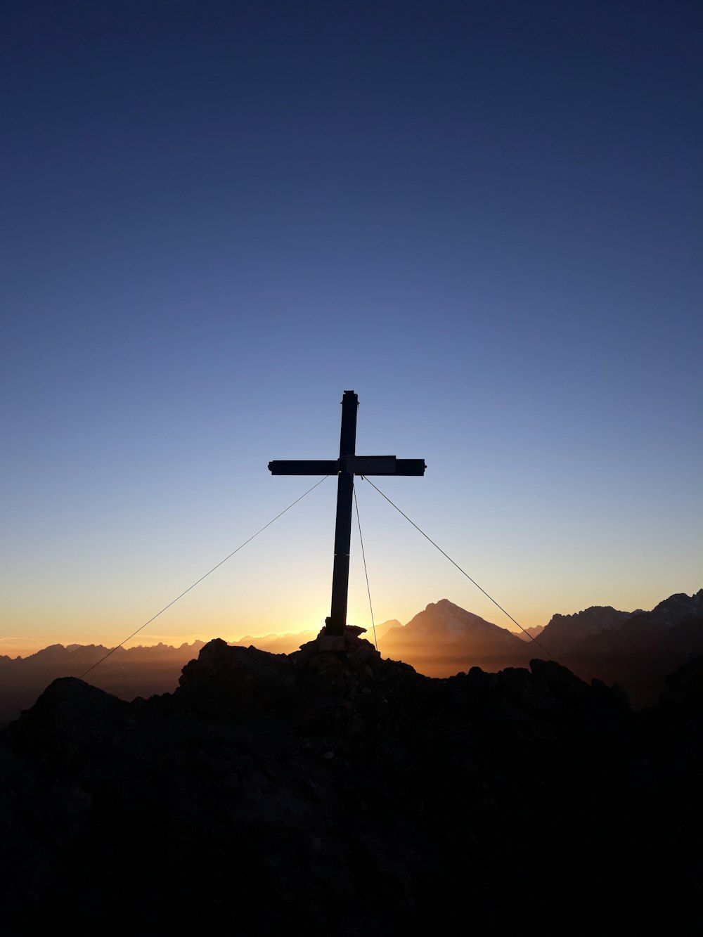 日没時の岩の上の十字架のシルエット