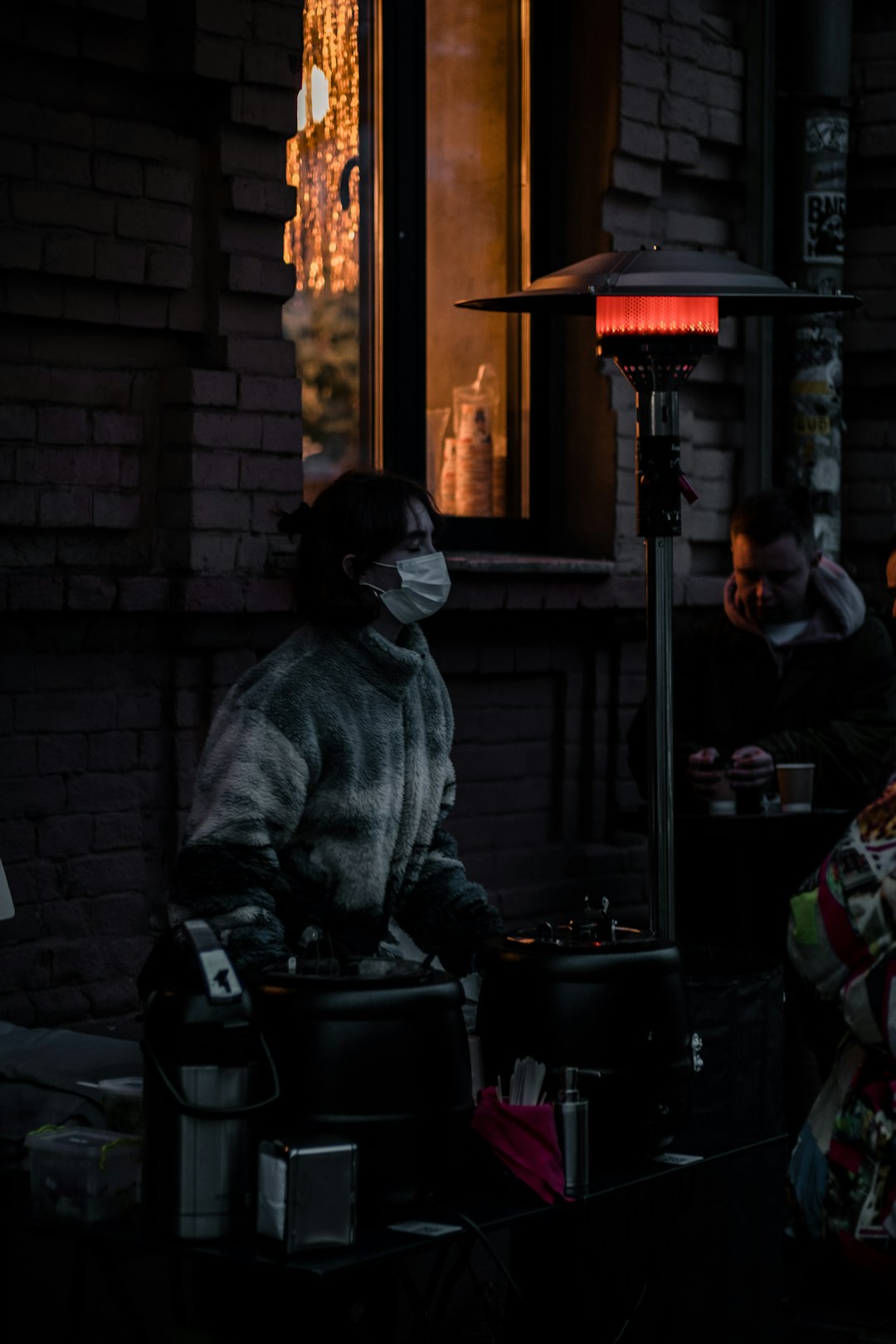  woman in gray fur coat standing near brown brick wall heater