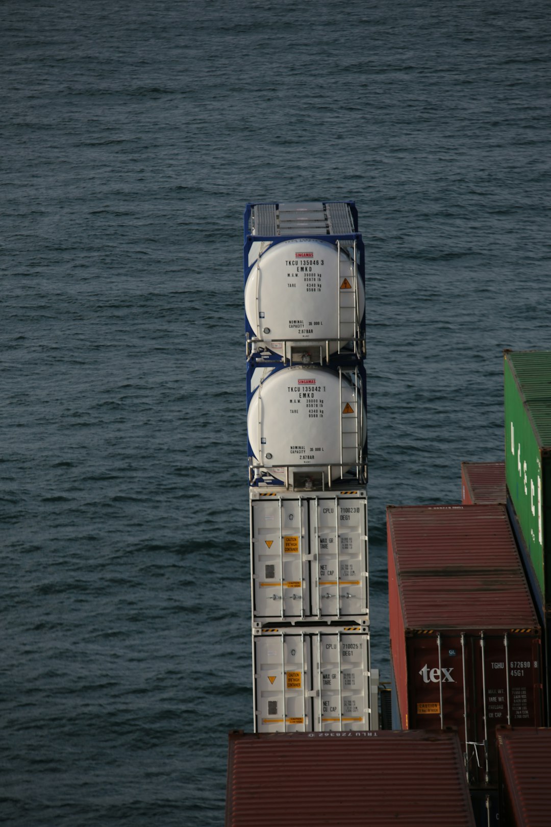 white and red cargo containers on body of water during daytime