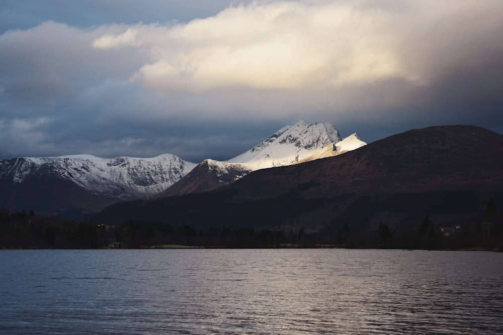 snow covered mountain near body of water during daytime