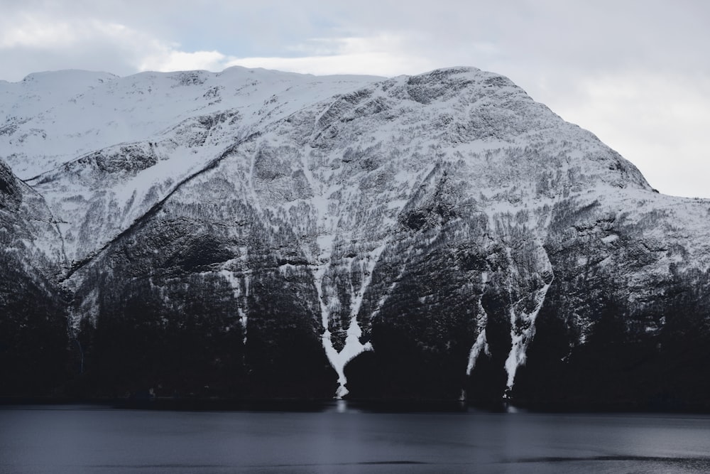 grayscale photo of mountain near body of water