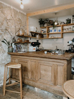 A cozy rustic kitchen counter displaying jars of homemade jams, fresh milled flour bags, and a steaming cup of mushroom coffee.