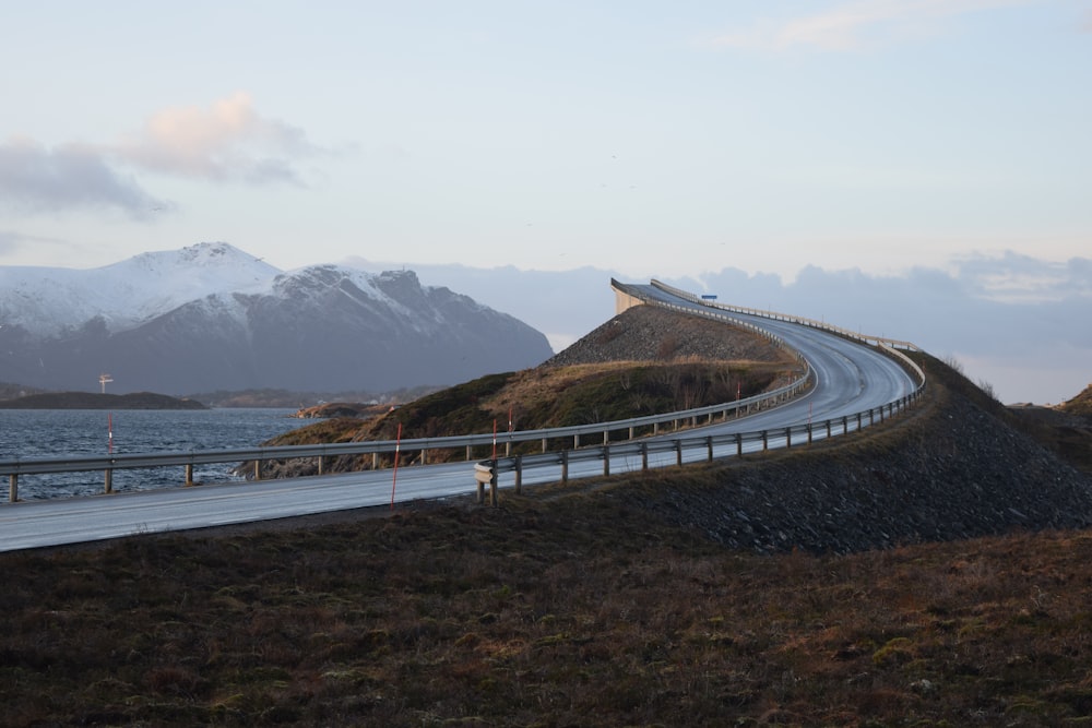 gray concrete road near body of water during daytime