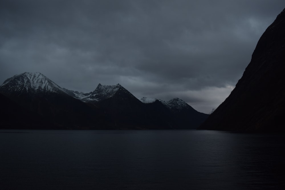 grayscale photo of mountain near body of water