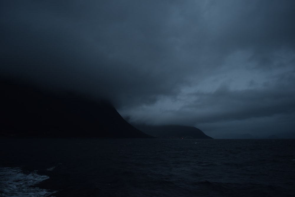 grayscale photo of mountain near body of water