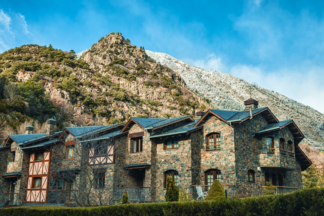 brown concrete building near green grass field and mountain during daytime