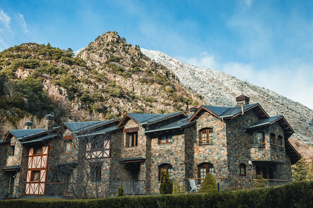 brown concrete building near green grass field and mountain during daytime