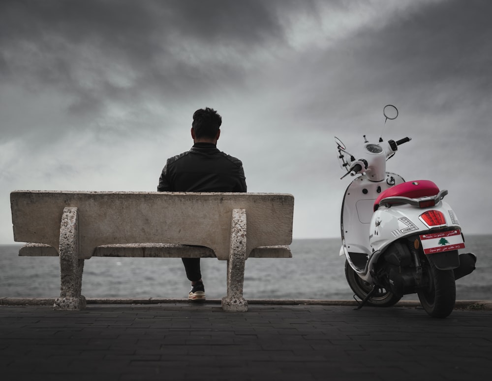 man in black jacket sitting on brown wooden bench during daytime