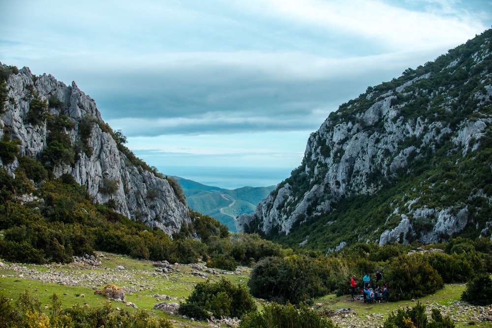 Campo de hierba verde cerca de la montaña rocosa gris bajo el cielo nublado blanco durante el día