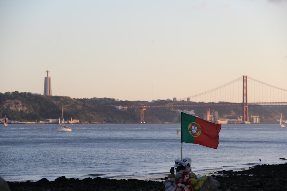 Una bandera en una playa con un puente al fondo