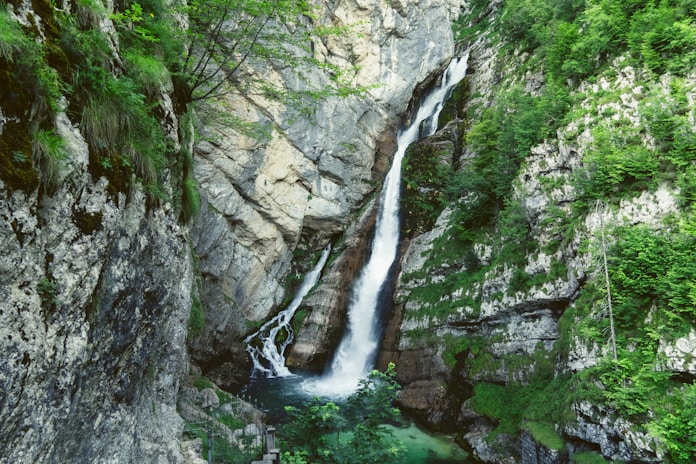 water falls between gray rocky mountain during daytime