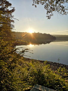 A peaceful nature scene with a person meditating by a calm lake at sunrise.