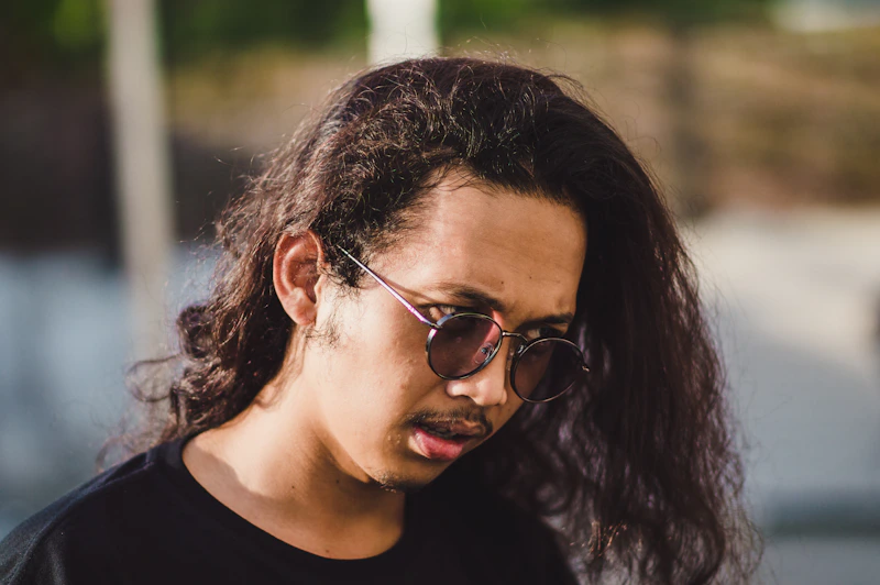 man with long hair and sunglasses on phone