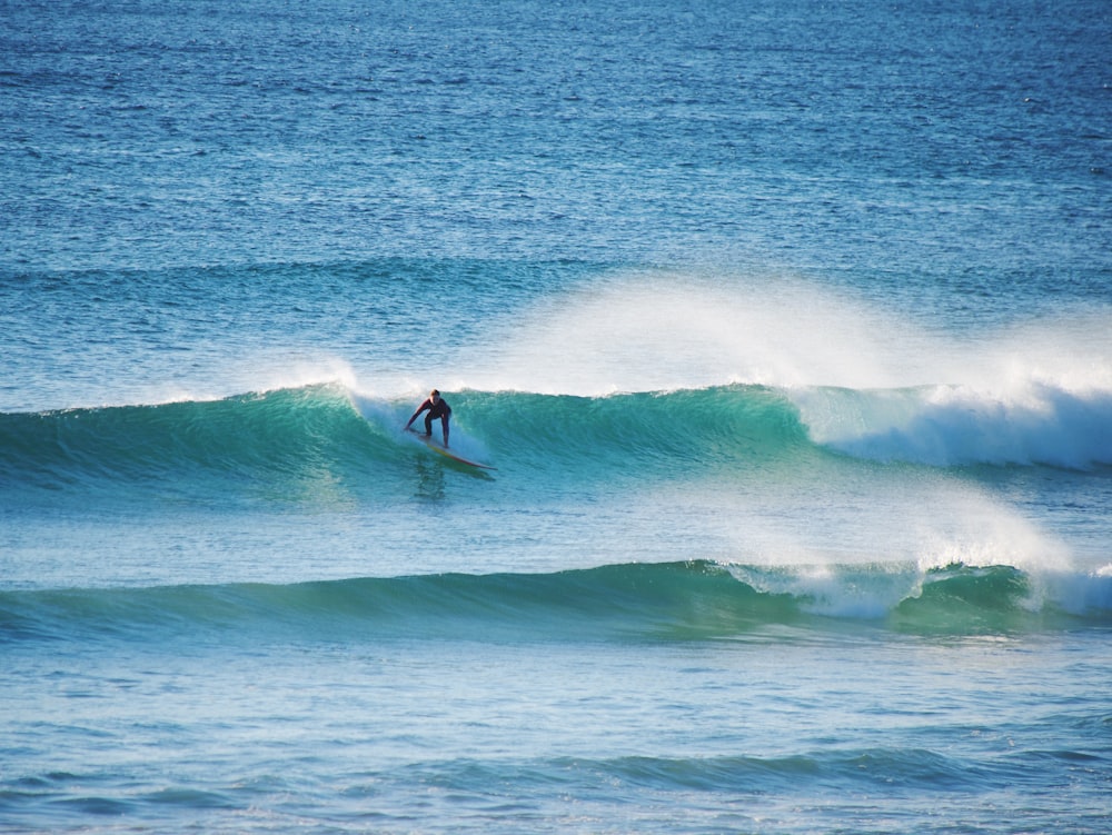 homem surfando nas ondas do mar durante o dia