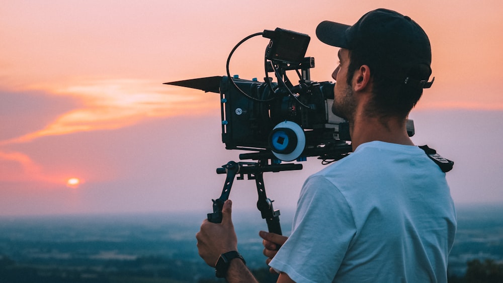 man in white shirt holding black video camera