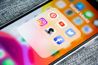 Social media app icons on a smartphone screen with a textured grey background