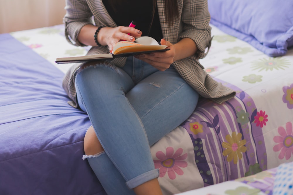 Femme en cardigan marron et jean en denim bleu assise sur un canapé fleuri violet et blanc