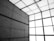 An architectural interior featuring a modern, industrial design with large stone or concrete panels on the walls. The ceiling consists of a grid of square lights, casting a diffused glow.