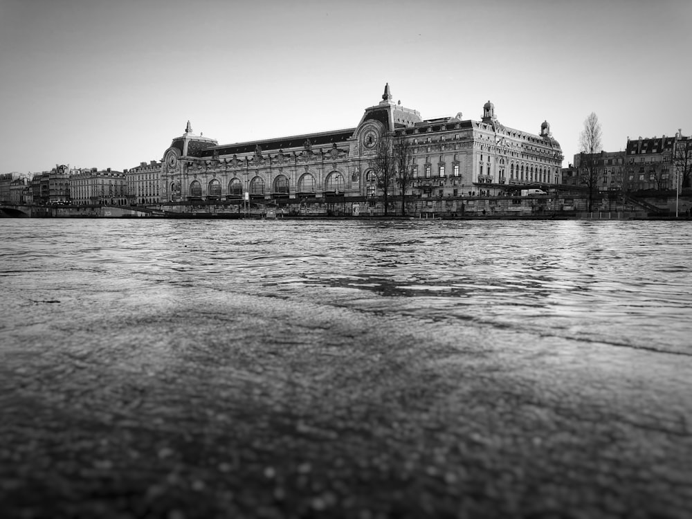 grayscale photo of concrete building near body of water