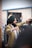 A person wearing a green turban and a light brown suit appears to be dancing or celebrating with arms raised. The atmosphere is lively, with other individuals in the background also appearing engaged, possibly at an event or gathering.