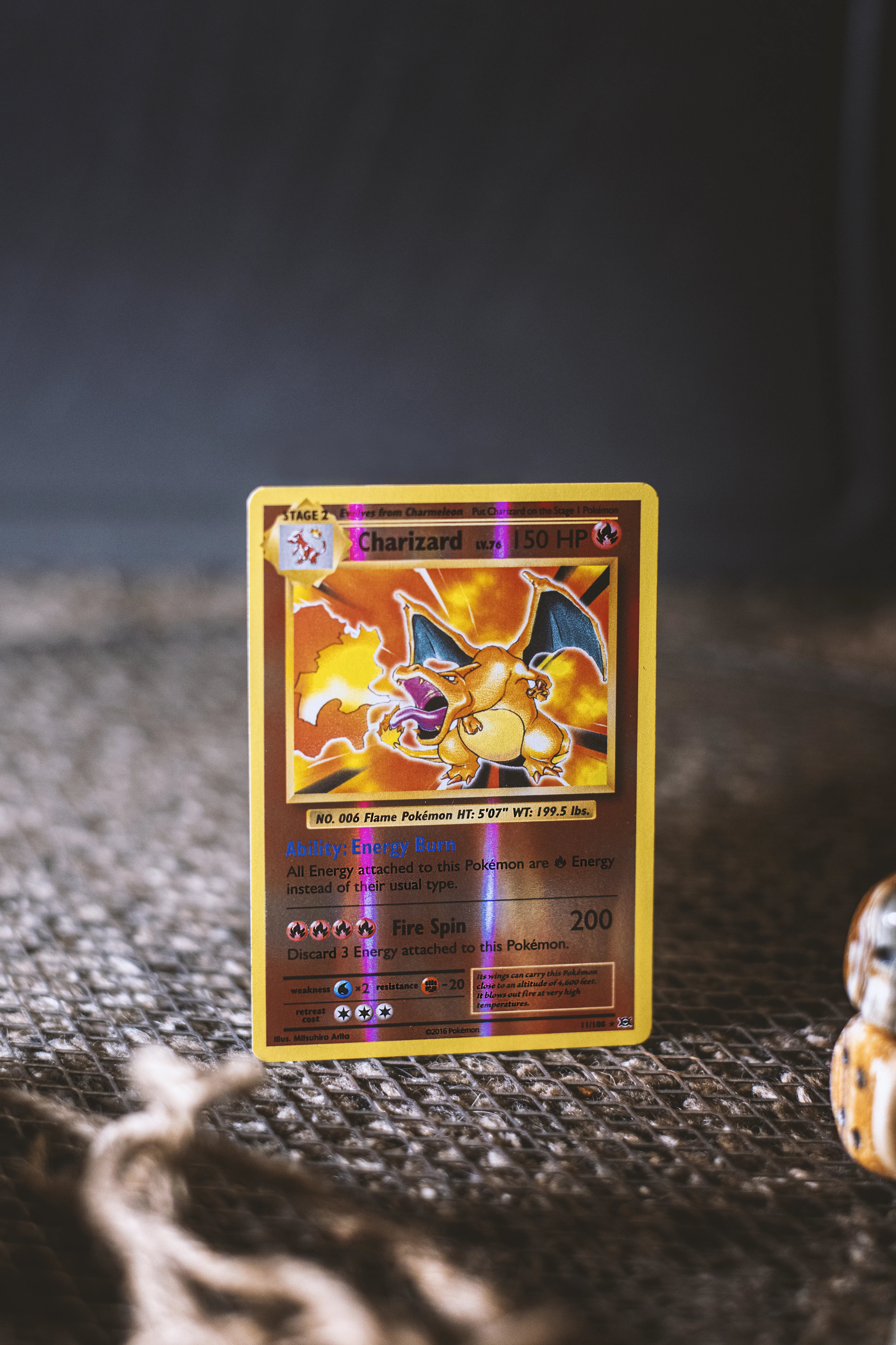 Carte à collectionner brillante représentant un dragon de feu, posée sur un tissu gris