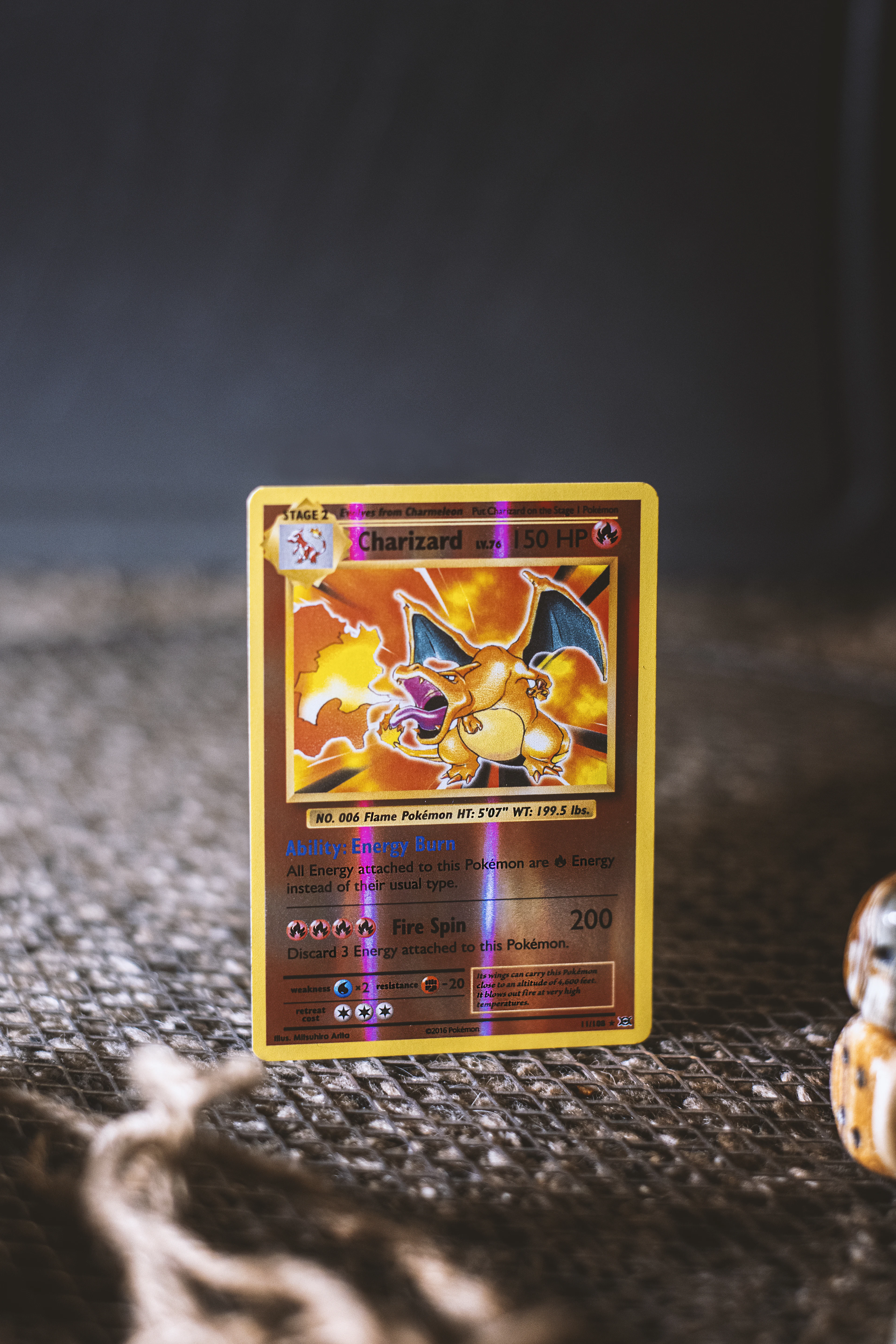 Carte à collectionner brillante représentant un dragon de feu, posée sur un tissu gris