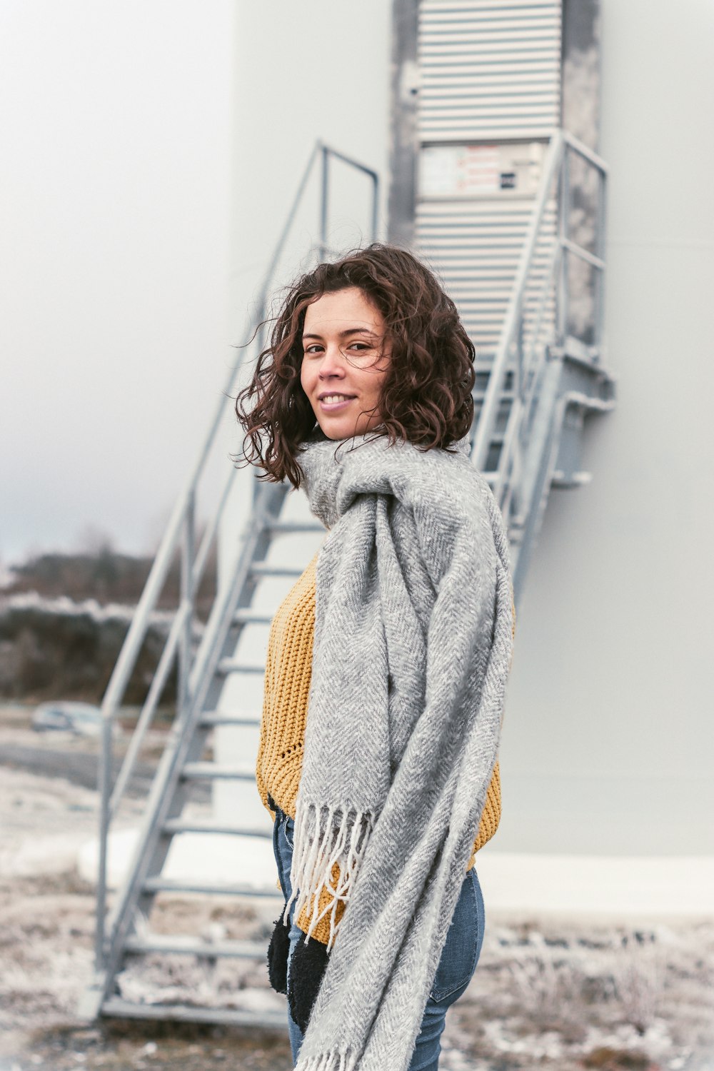 woman in gray scarf standing on beach during daytime