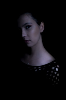 Portrait of Livi Arriaga Ruiz sitting in a dimly lit room, expression intense and thoughtful.