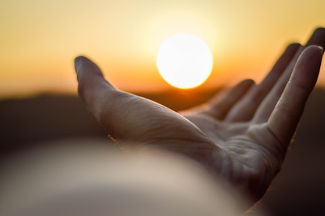 left hand extended towards the sun representing healing