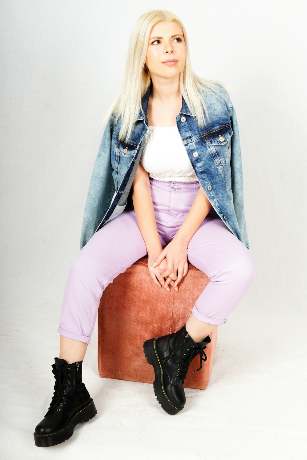 woman in blue denim jacket and black pants sitting on brown wooden seat