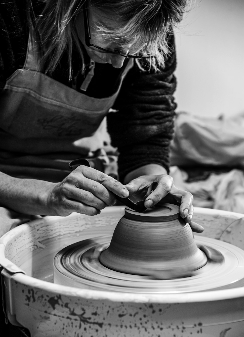 person making clay pot in grayscale photography