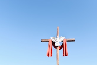 brown wooden cross with red and white ribbon