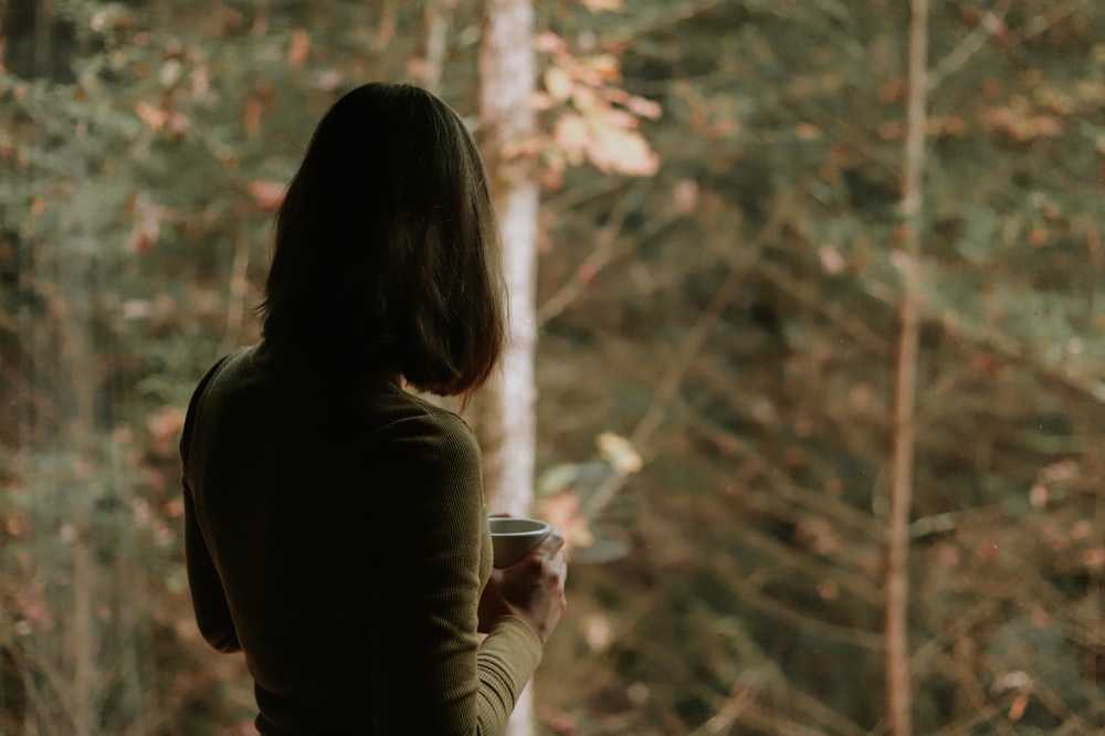 woman in brown long sleeve shirt holding white ceramic mug