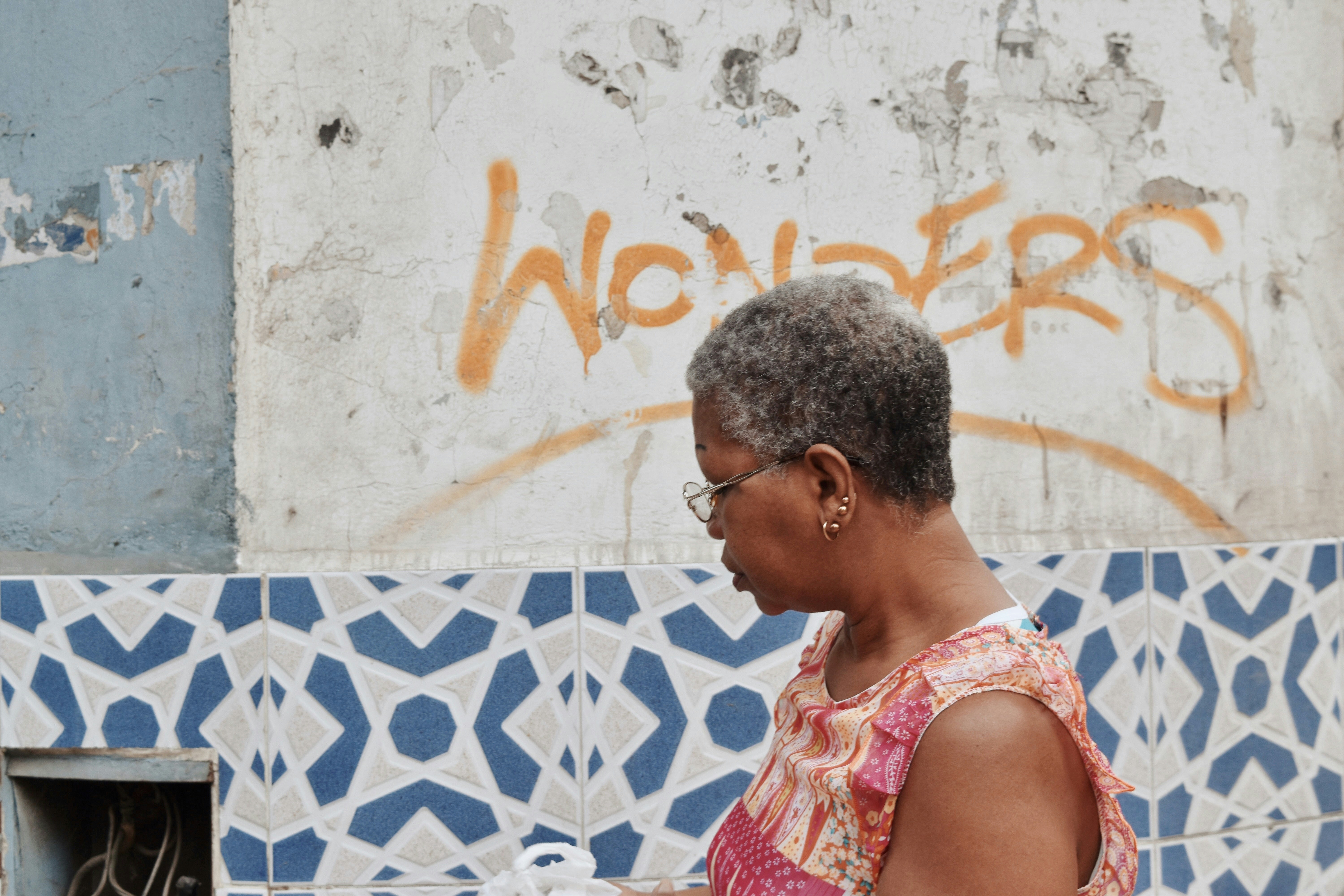 woman in pink and white sleeveless dress standing beside white wall