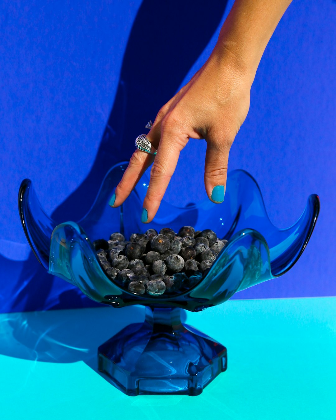 person holding black round fruit