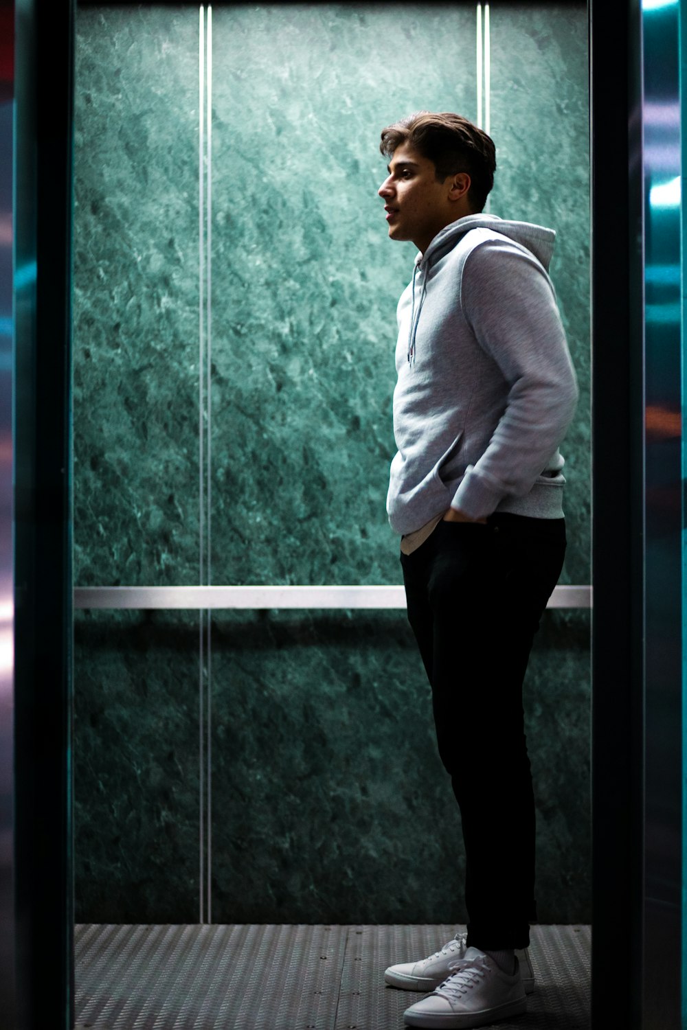 man in white dress shirt and black pants standing beside glass window