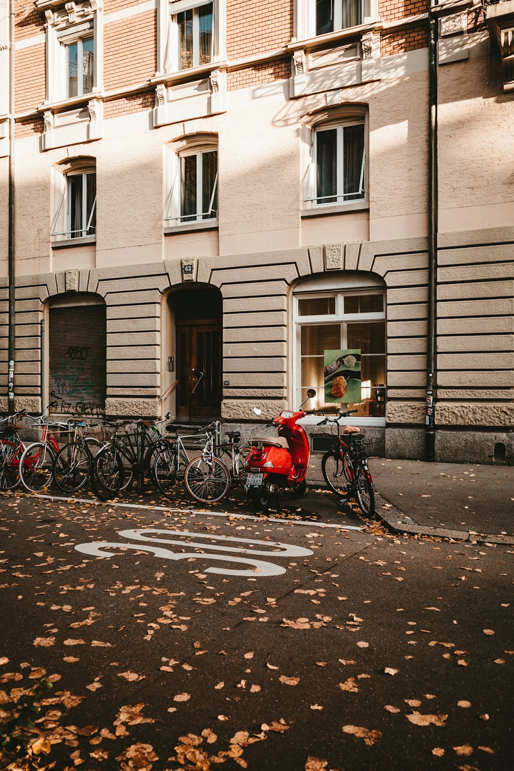 red and black bicycles parked beside brown concrete building during daytime