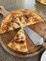 A Viking-style pizza cutter with a high carbon steel blade and carved wooden handle on a kitchen counter.